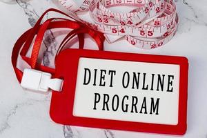 Diet online program text on a red name tag with measure tap on white desk. photo