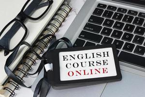 texto en línea del curso de inglés escrito en una etiqueta de nombre negra colocada en una computadora portátil. foto