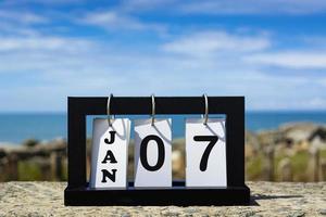 Jan 09 calendar date text on wooden frame with blurred background of ocean photo