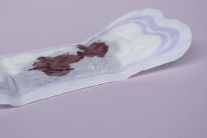 Menstrual blood on a sanitary pad on pink background. Flat lay photo