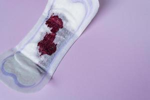 Menstrual blood on a sanitary pad on pink background. Directly above. Flat lay photo