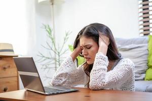 Young woman with laptop computer, office worker tired and has a headache.