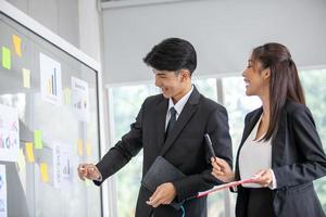 Business people meeting at office and use post it notes to share idea. businessman and businesswoman putting colorful sticky notes on glass window in office. photo