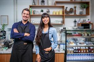 Portrait of smiling owner standing at his cafe. Coffee owner standing in front of coffee shop to welcome customer and open the coffee shop in morning. photo
