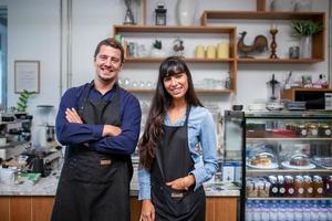 Portrait of smiling owner standing at his cafe. Coffee owner standing in front of coffee shop to welcome customer and open the coffee shop in morning. photo