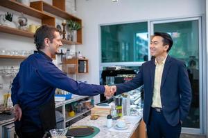 happy barista take order with tablet from customer in coffee shop. restaurant owner and customer shake hands. photo