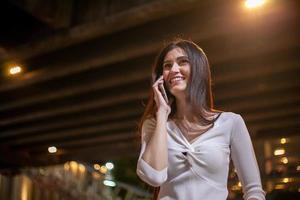 Beautiful woman use of mobile phone in city street at night photo