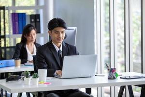 Portrait of Asian handsome man working at the office, using computer on table. photo