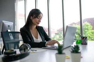 Portrait of Asian beautiful business woman working at the office, using computer on table. photo