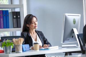 Portrait of Asian beautiful business woman working at the office, using computer on table. photo