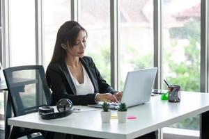 Portrait of Asian beautiful business woman working at the office, using computer on table. photo