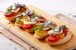 crostini con anchoas, tomates y huevo, decorado con verduras foto