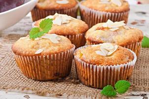 Muffins with plums and almond petals decorated with mint leaves photo