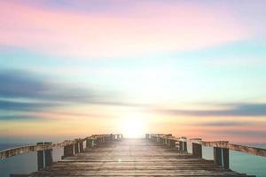 A wooden bridge jutting out into the sea with a beautiful view. photo
