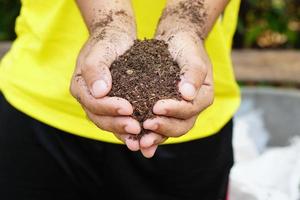 el suelo fértil se usa para cultivar plantas en manos humanas. foto