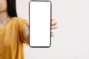 concepto de uso del teléfono inteligente. un teléfono inteligente con una pantalla blanca en blanco en manos de una mujer. foto