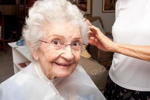 anciana cortándose el pelo en la comodidad de su hogar foto