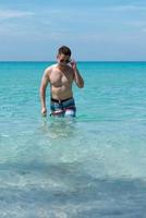 Portrait of Mature Asian Man Walking From Sea to Beach photo