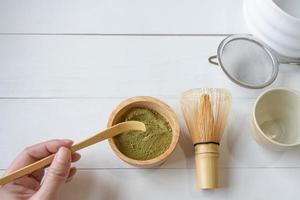 Woman Using Spoon to scoop Matcha Green Tea Powder to Make Japanese Traditional Tea photo