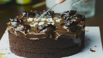 Schneiden Sie den Kuchen für die Geburtstagsfeier mit einem Plastikmesser in 4 Teile. Schokoladenkuchen mit weichem Gesicht. video
