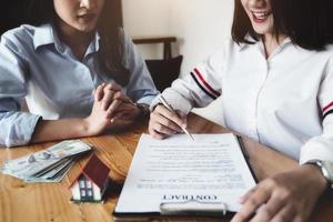 The customer holds a pen and reads the conditions in order to sign a house purchase contract with home insurance documents with the salesperson. photo