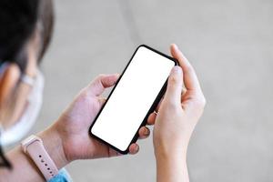 una mujer sosteniendo un teléfono celular con una pantalla blanca en blanco. el espacio en blanco en la pantalla blanca se puede usar para escribir un mensaje o colocar una imagen. foto