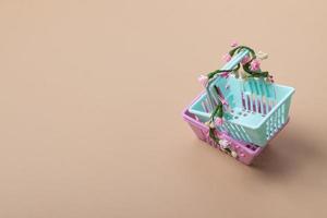 Empty shopping basket with flowers on a beige background. Minimalism. Spring sales, shopping, prices concept photo