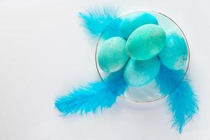 Composition of blue easter eggs and feathers on a light background. photo