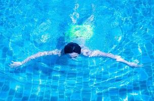 Men are swimming or diving in the pool. Young man exercising or relaxing in the outdoor pool. photo