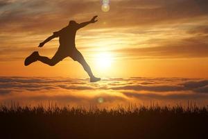 The silhouette of a man is jumping forward. The concept of clawing through hurdles photo