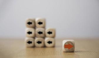 Red arrow on wooden move on different direction with black arrow on cube for business and technology disruption or unique concept. photo