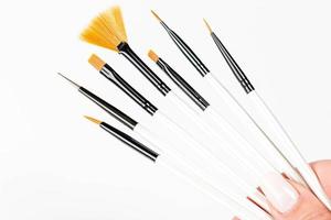 Various makeup brushes in a woman's hand on a white background photo