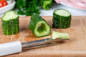 Fresh cucumber slices and knife on wooden kitchen board