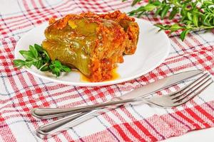Stuffed bell peppers with tomato sauce on a kitchen towel with a knife and fork photo