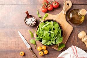 Fresh arugula leaves in brown bowl with fresh vegetables photo