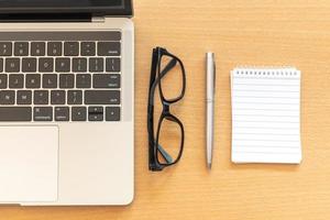 Top view desk with notepad and laptop on office wooden table photo