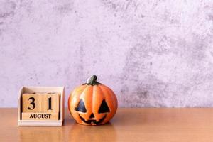 Wooden calendar block disrupted show date 31 october halloween day and toy pumpkin on wooden background. Halloween concept photo