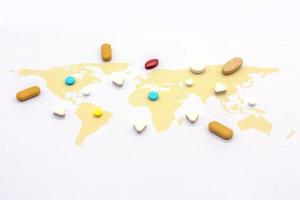 Colorful pills on world map on white blackground photo