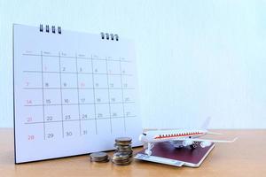 modelo de avión con calendario de papel sobre mesa de madera. plan de viaje foto