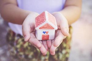 Small kid hands holding house photo