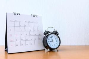 calendario con dias y reloj en mesa de madera foto