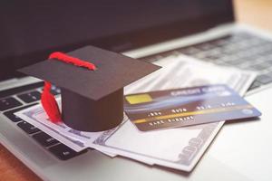 Credit card, Academic hat model and Notebook on wooden desk. Online payment by using laptop photo