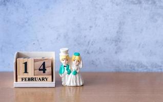 pareja de bodas en miniatura con calendario de madera 14 de febrero. día de San Valentín foto