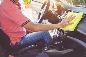 Hombre limpiando el coche con un paño de microfibra foto