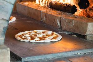 Thin crust pizza baking in wood fired oven photo