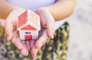 Small kid hands holding house photo