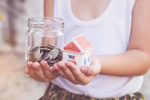 Small kid hands holding house and coins photo