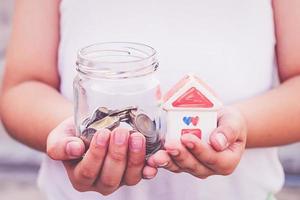 Small kid hands holding house and coins photo