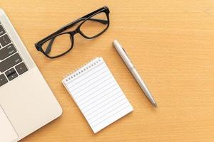 Top view desk with notepad and laptop on office wooden table photo