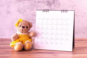 oso de peluche con calendario en mesa de madera. celebración del día de san valentín